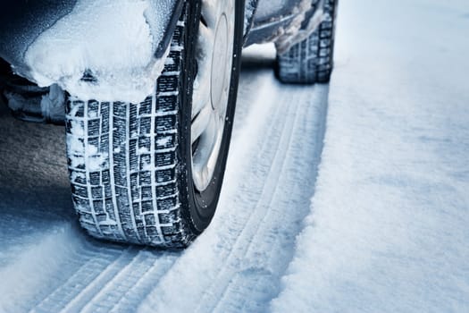 Closeup of car tires in winter on the road covered with snow