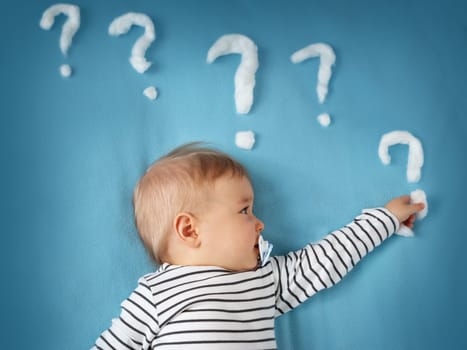 little boy lying on blue blanket with lots of question marks