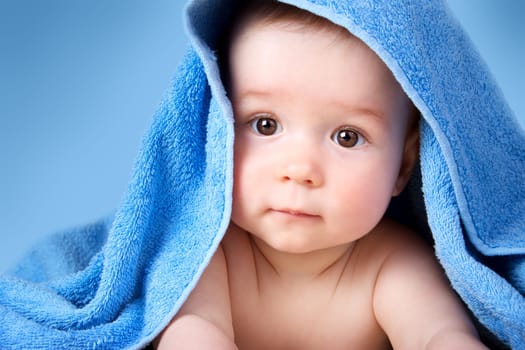 Cute eight month old baby wrapped in a towel. Baby hygiene. Adorable little boy