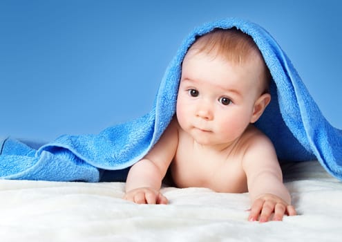 Cute eight month old baby wrapped in a towel. Baby hygiene. Adorable little boy