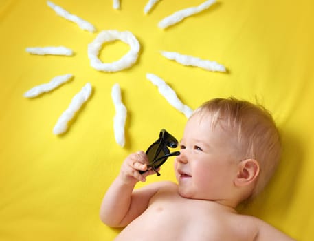 little boy with sunglasses and sun shape on yellow blanket