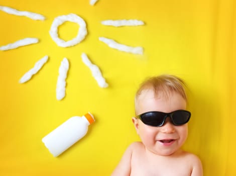 little boy with sunglasses and sun shape on yellow blanket