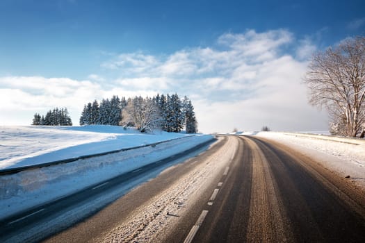 Asphalt road in snowy winter on beautiful frosty sunny day