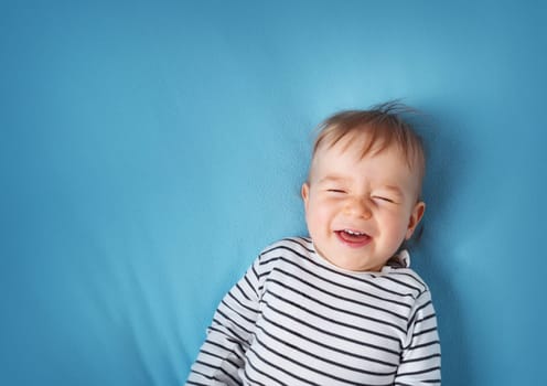 happy little boy on blue blanket background