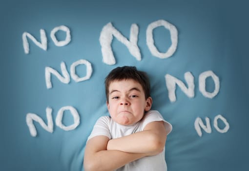 bad boy on blue blanket background. Angry child with no words around