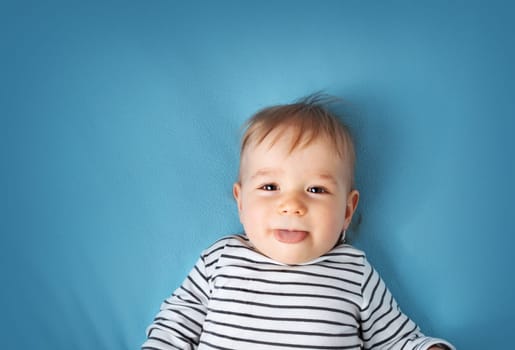 happy little boy on blue blanket background