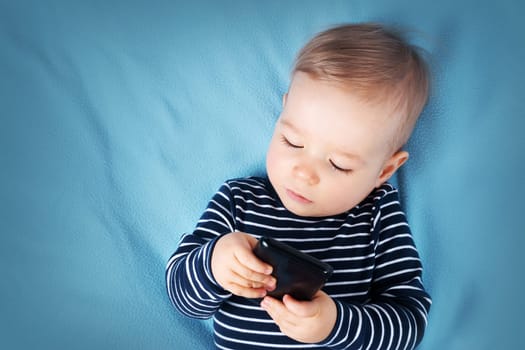 little boy on blue blanket background withcellphone