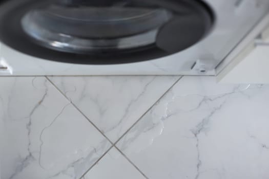 Spilled water leaked from washing machine built into the kitchen furniture. Spilled water on the tiled floor, flooding
