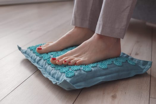 Female feet standing on acupressure mat. Self acupuncture massage. Woman having alternative medicine treatment.