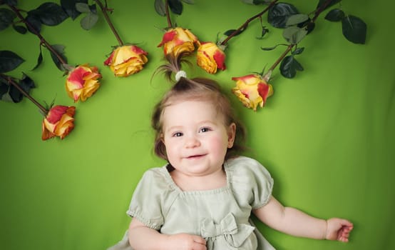 pretty one year old babygirl lying on green blanket with yellow roses