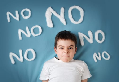 bad boy on blue blanket background. Angry child with no words around
