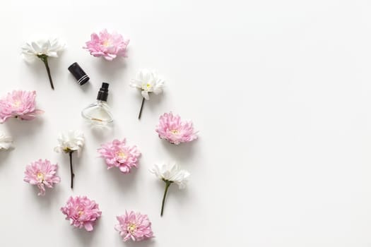 Flat lay composition with spring flowers and perfume jar isolated on white background. Top view, flat lay