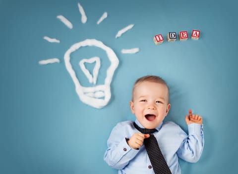 One year old boy with a bulb on blue background. Child with an idea