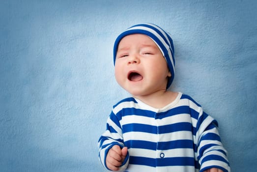 sleepy little boy crying on soft blue blanket