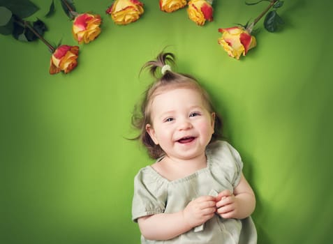 pretty one year old babygirl lying on green blanket with yellow roses