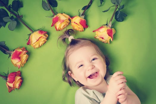 pretty one year old babygirl lying on green blanket with yellow roses