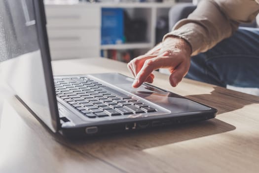 Closeup of men's hand on laptop computer. User at home surfing in the internet