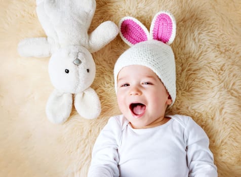 sleepy one year old baby lying in bunny hat on lamb wool background