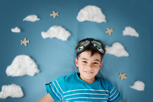 boy lying on blanket with white clouds in pilot glasses