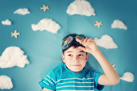 boy lying on blanket with white clouds in pilot glasses