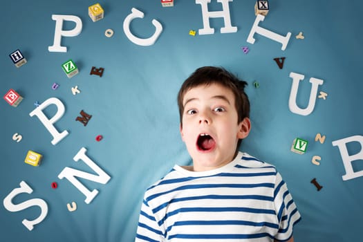 seven years old child lying with letters on blue background