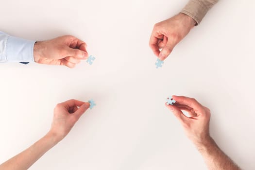 Hands with puzzle items isolated on white background. Team problem solving. Top view. Mutual assistance of business and individuals