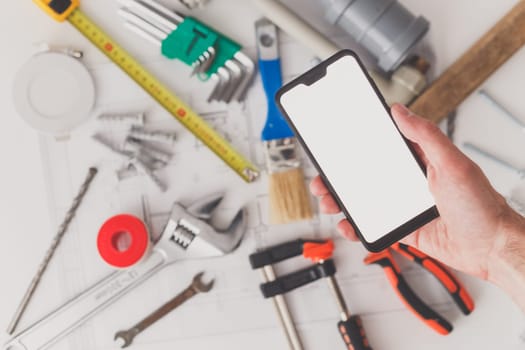 Smartphone with blank screen with drawing and building supplies in the background
