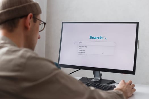 Unemployed man looking for work on the internet sitting at the computer at home.