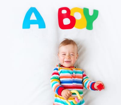 Baby boy lying on soft blanket with letters above