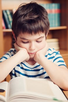 seven years old child reading a book at home