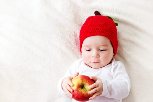 7 month old baby lying inbed with apple