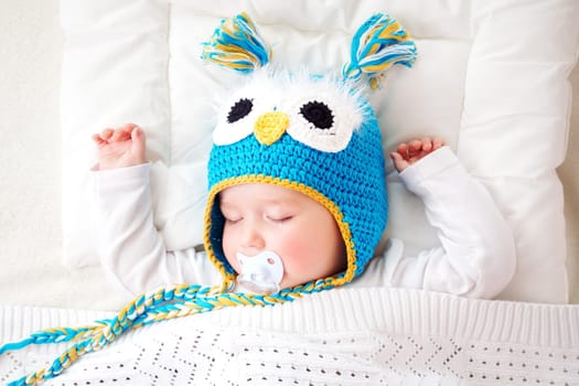 seven month old boy sleeping in the bed in owl hat