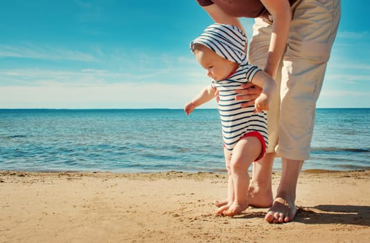 Nine month old baby boy walking on the beach in beautiful summer day