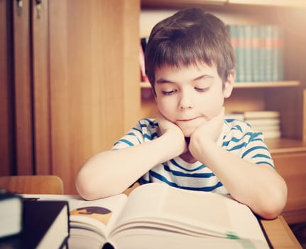 seven years old child reading a book at home