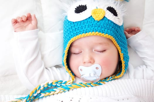 seven month old boy sleeping in the bed in owl hat