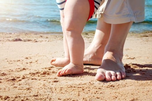 Nine month old baby boy walking on the beach in beautiful summer day