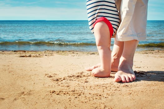 Nine month old baby boy walking on the beach in beautiful summer day