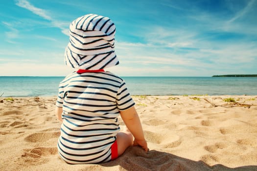 Nine month old baby boy sitting on the beach in beautiful summer day