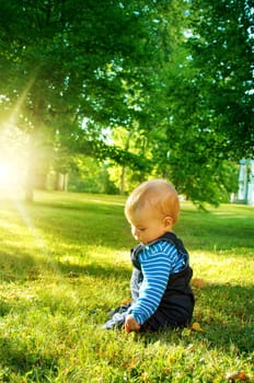 little nine month old baby sitting in the park in beautiful evening