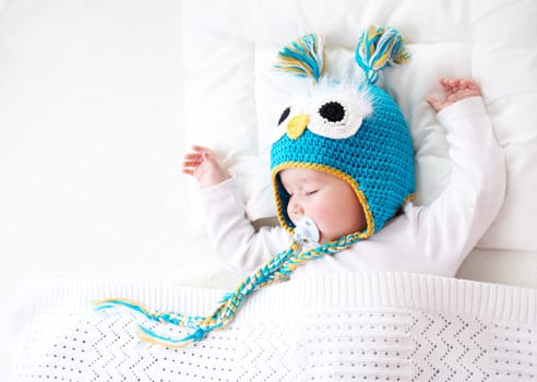seven month old boy sleeping in the bed in owl hat