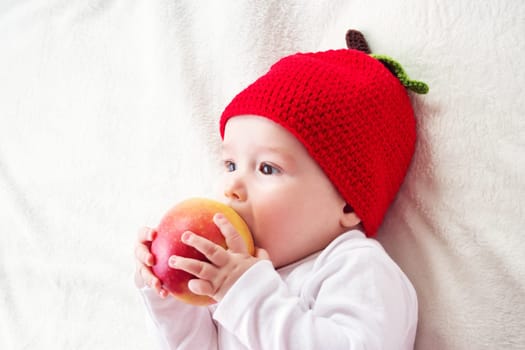 7 month old baby lying inbed with apple