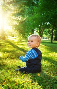 little nine month old baby sitting in the park in beautiful evening