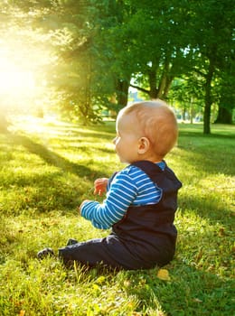 little nine month old baby sitting in the park in beautiful evening