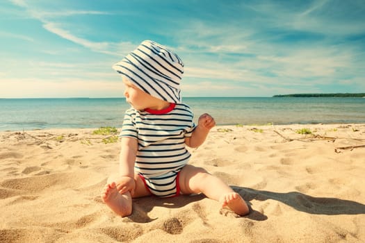Nine month old baby boy sitting on the beach in beautiful summer day