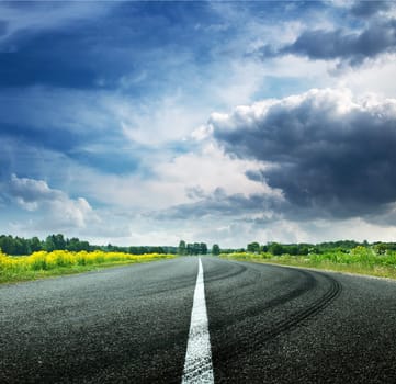 asphalt road view in countryside on sunny summer day with dramatic clouds