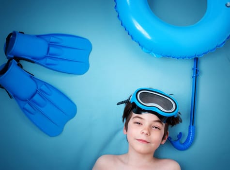Child lying on blue blanket with swimming mask and flippers