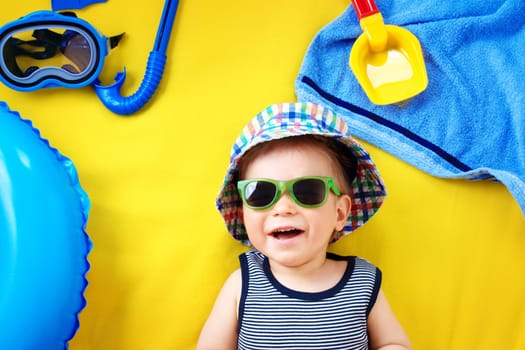 little boy with sunglasses in hat on yellow blanket