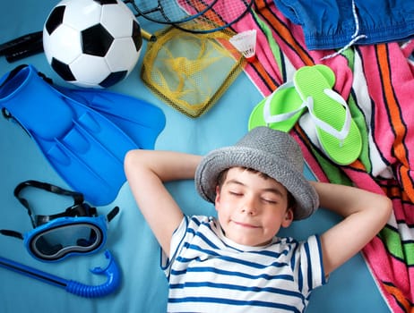 boy in straw hat with towel and toys on blue blanket