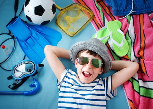 boy with sunglasses and toys on blue blanket