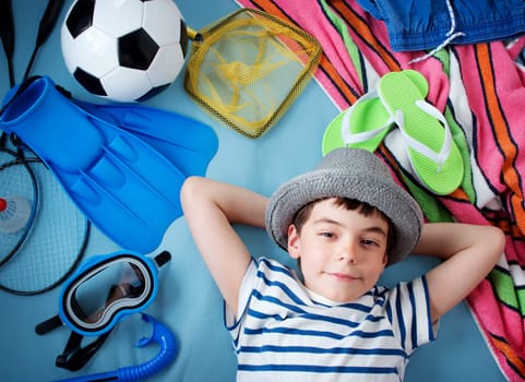 boy in straw hat with towel and toys on blue blanket